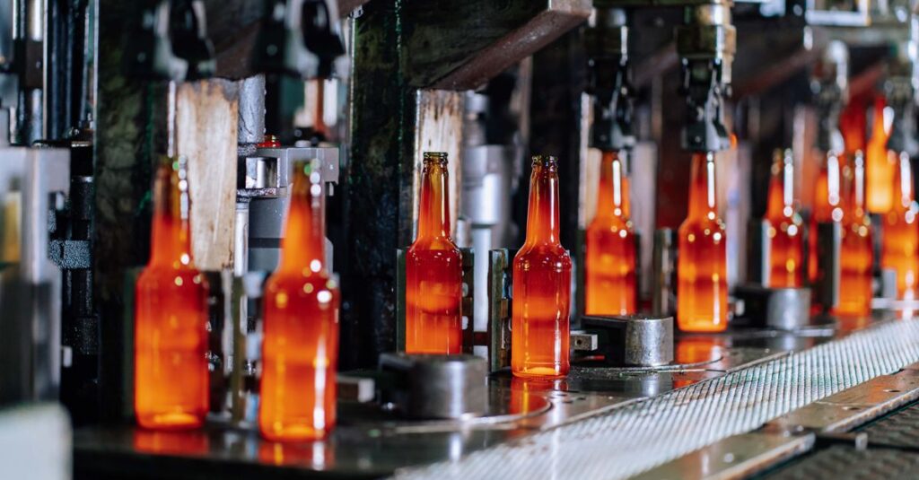 Glass bottles on a production line in a modern glass factory, showcasing industrial automation.