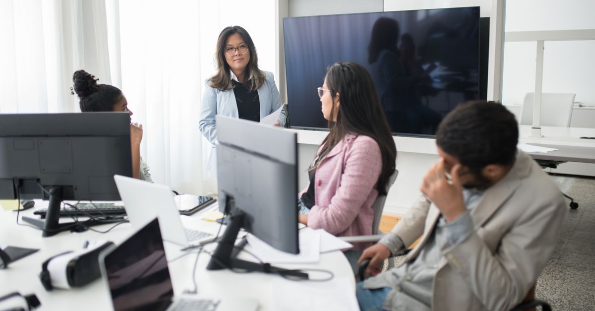 Professional team collaborating in a modern office environment with computers and screens.