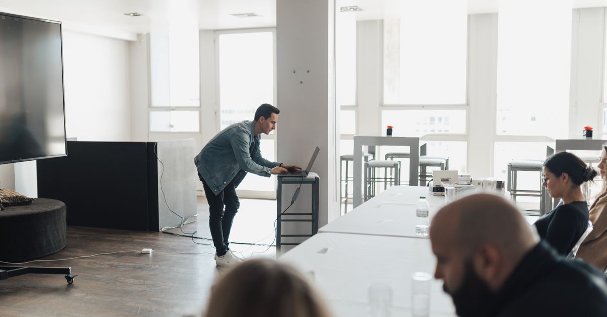 A professional presenting in a bright modern office setting to attentive colleagues.