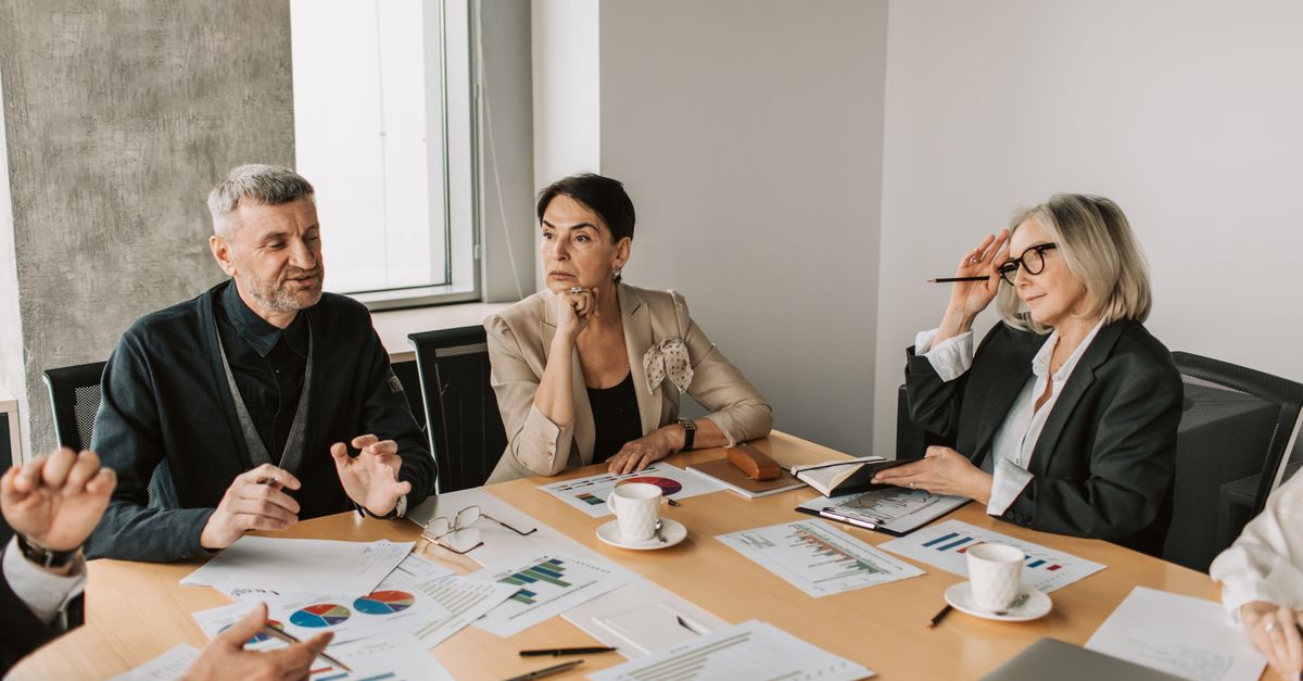 Diverse group of business professionals in a strategic meeting discussing documents and charts.