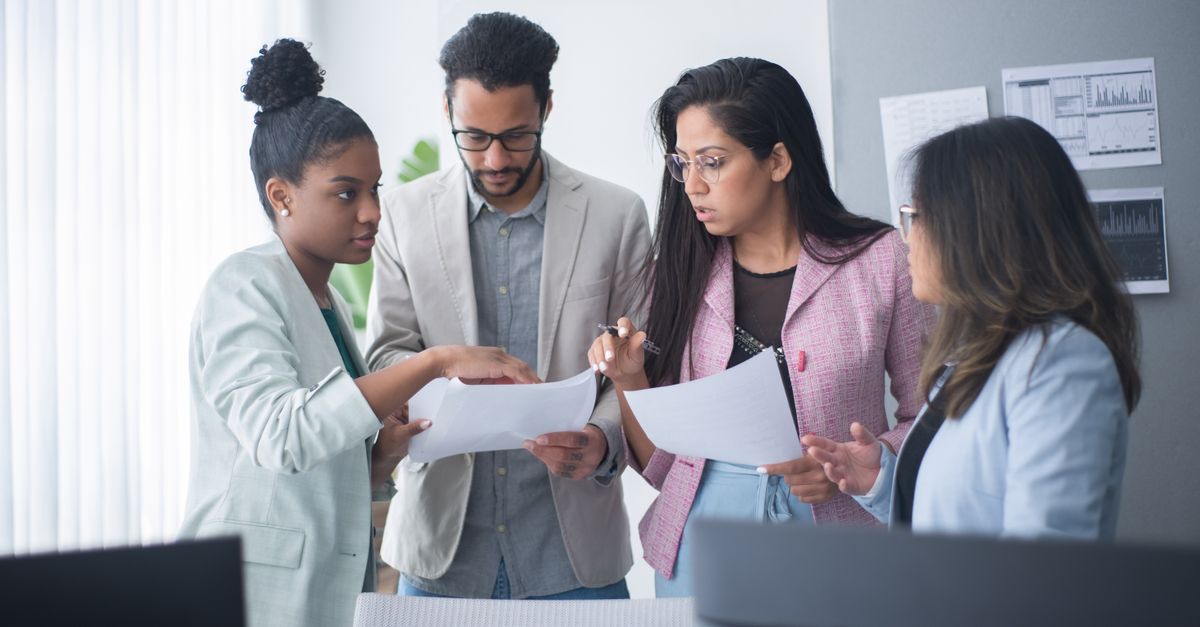 A diverse group of professionals engaged in a focused team meeting within an office environment.