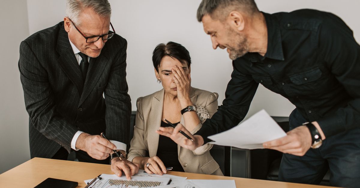 Business team in a tense meeting analyzing charts and reports at an office desk.