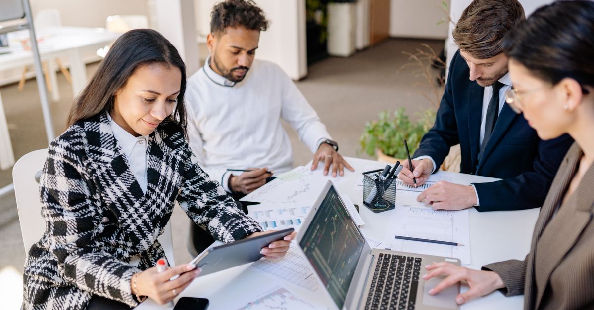 Business team engaged in planning and analysis with laptops and papers at a modern office.