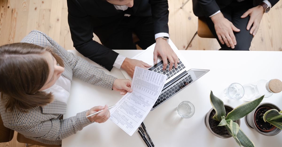 Overhead view of colleagues collaborating at a desk with laptop and documents in a business meeting.