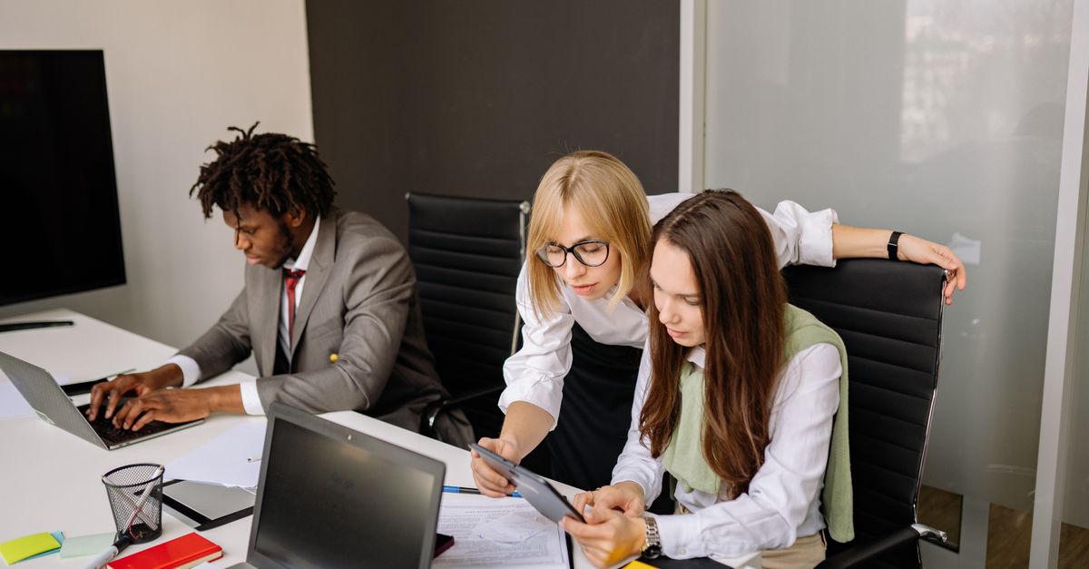 Business team collaborating in a modern office setting with laptops and tablets.