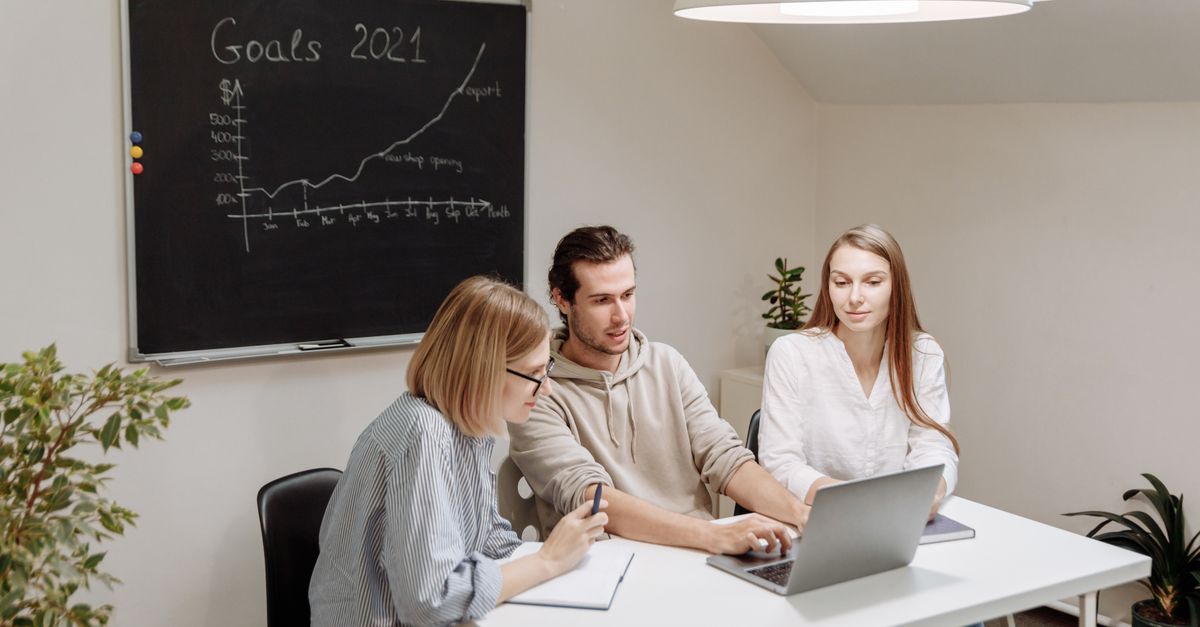Coworkers collaborate in a modern office setting, planning and discussing 2021 goals.
