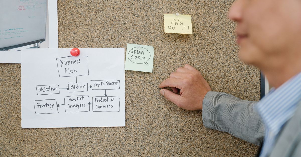 Office worker analyzing business plan on corkboard, boosting teamwork and strategic planning.