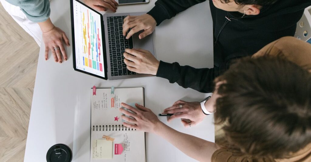 A high-angle view of a team collaborating over a laptop and notebook in a modern office.