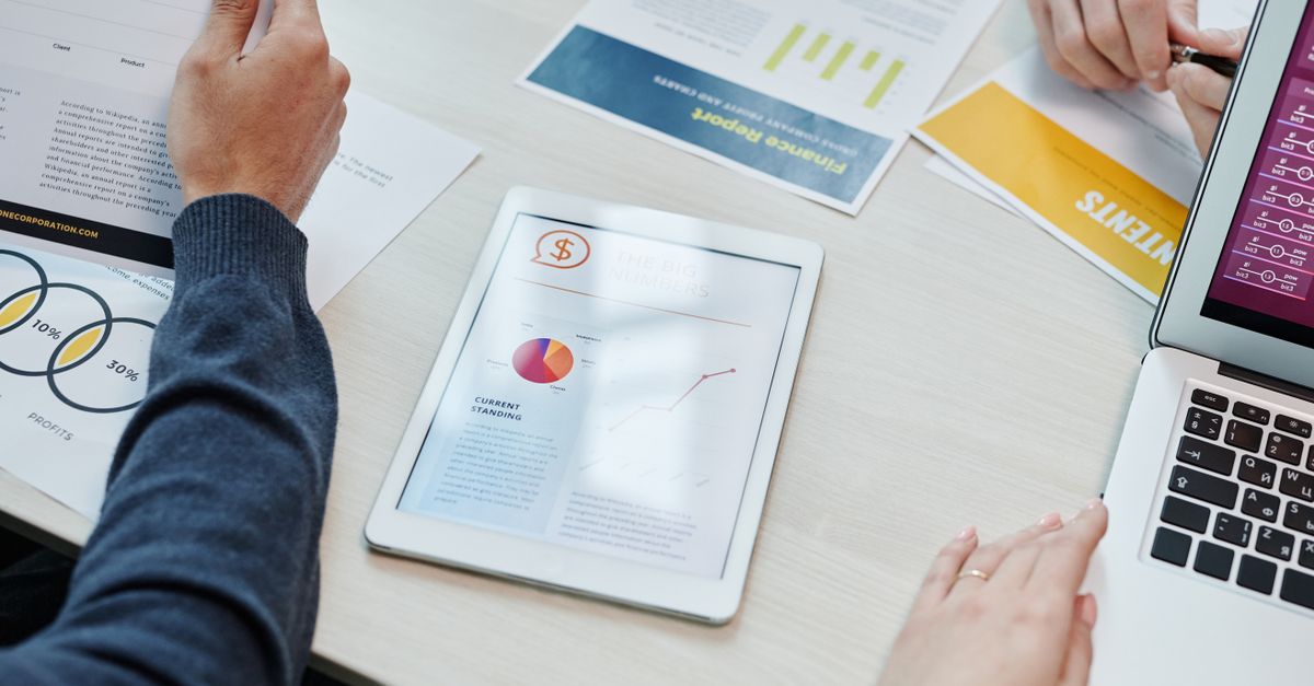 Top view of a business meeting table with digital devices and financial documents, showing collaboration.