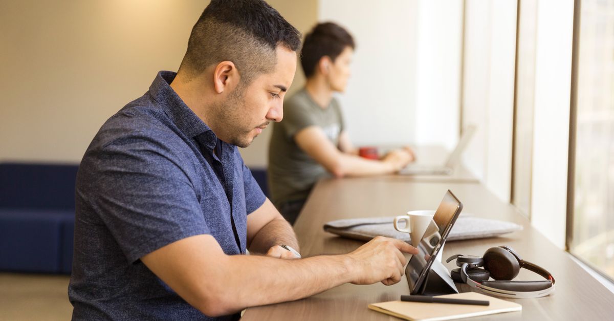 Two men working on devices in a modern office setting, emphasizing technology and collaboration.