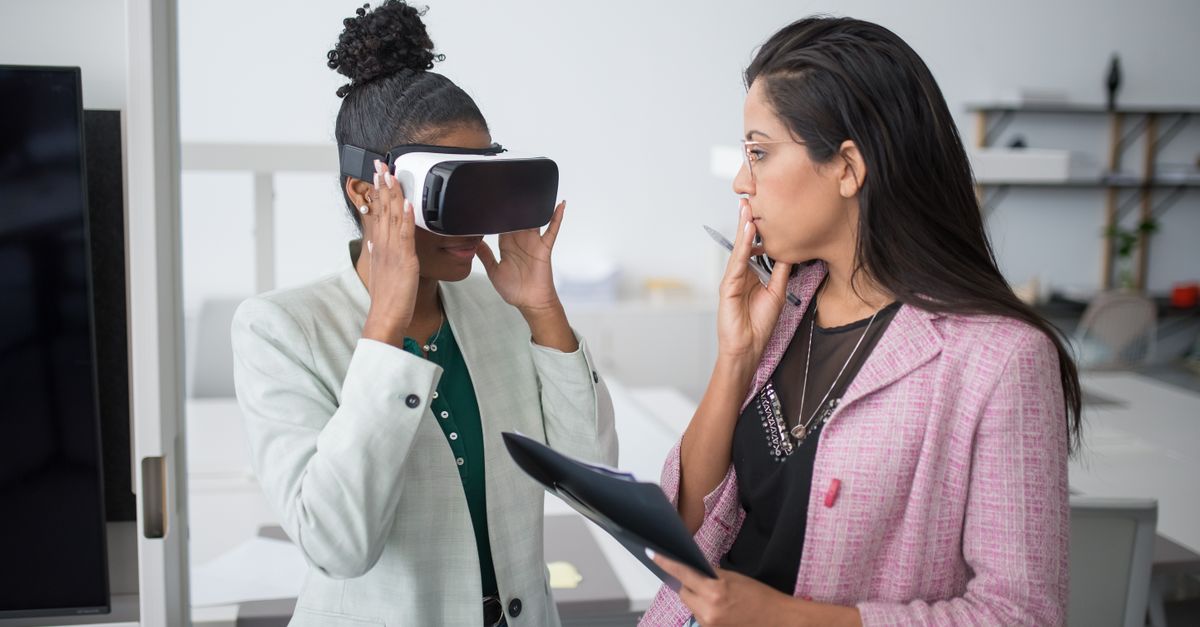 Two professional women collaborating using VR technology in a modern office setting, showcasing innovation.