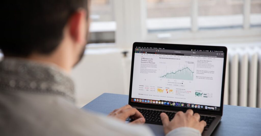 A person working on a laptop analyzing financial data in a bright indoor setting.