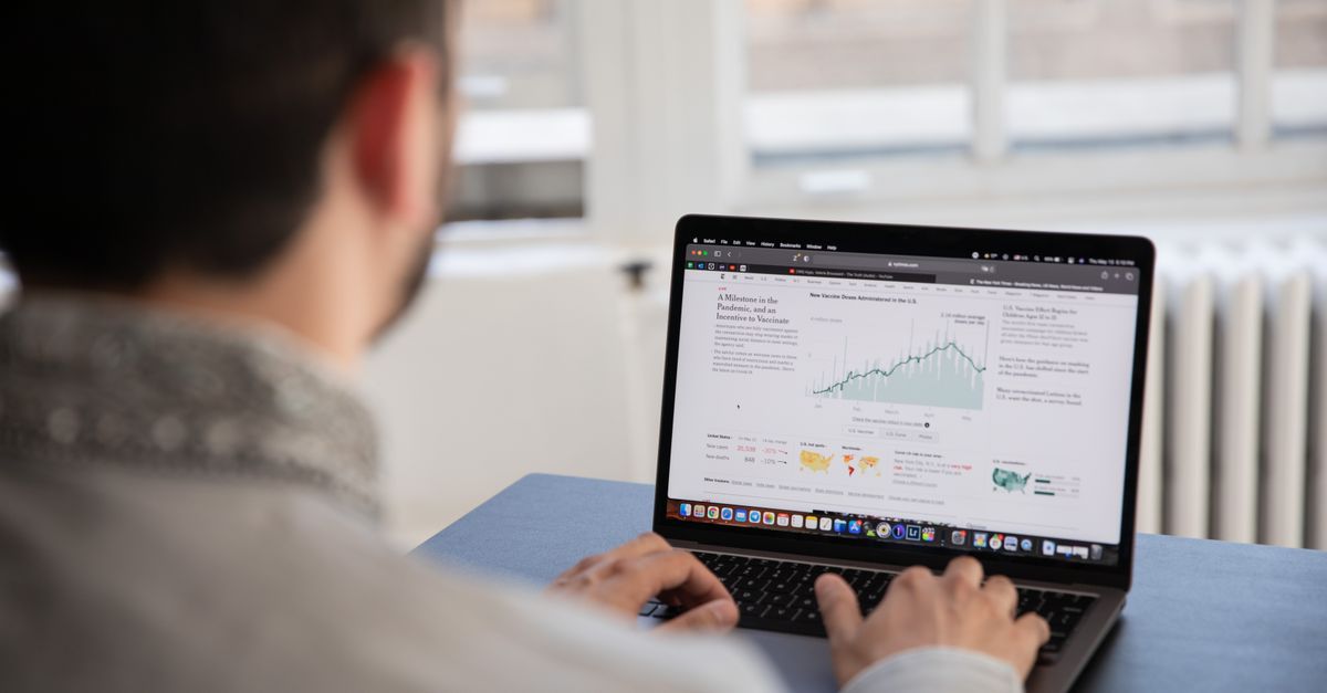 A person working on a laptop analyzing financial data in a bright indoor setting.