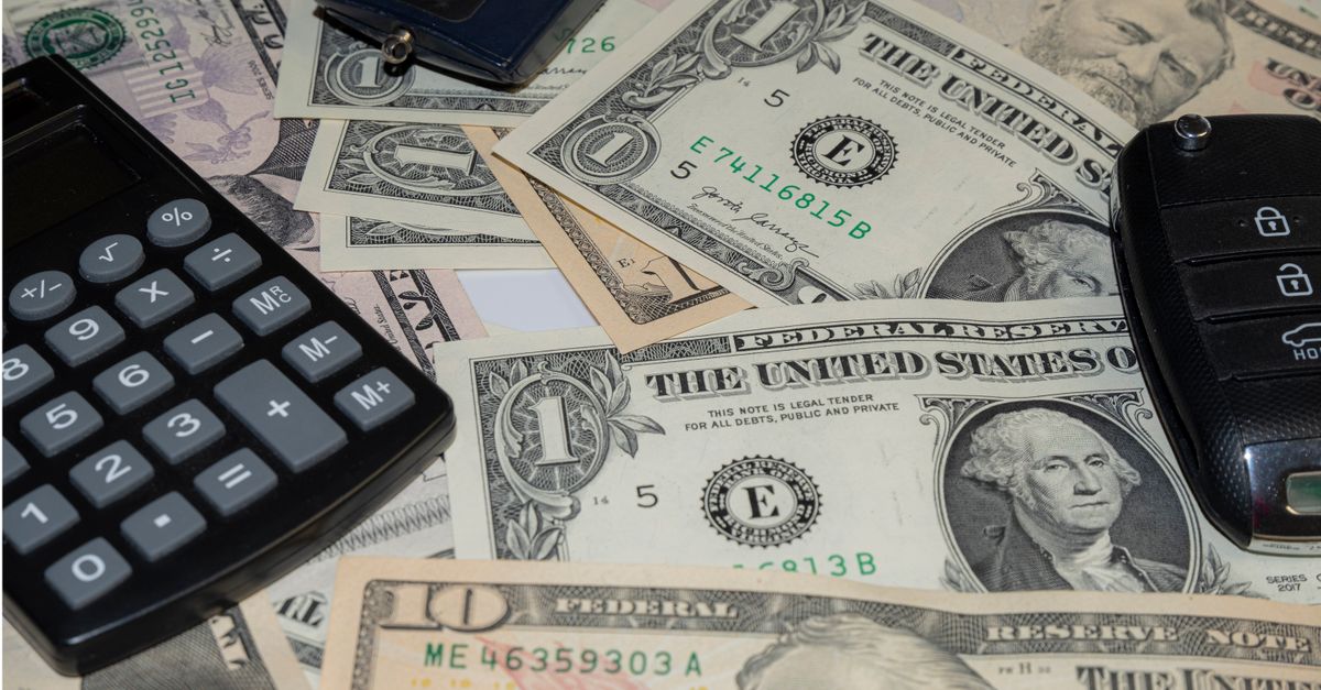 Close-up of various US banknotes, calculator, and car key illustrating finance concept.