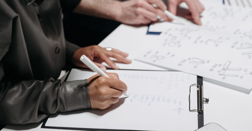 Close-up of team members taking notes and sketching designs during a meeting.