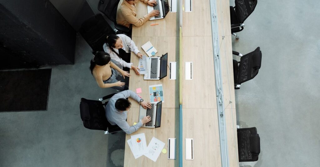 High angle view of colleagues working together on laptops in a modern office setting.
