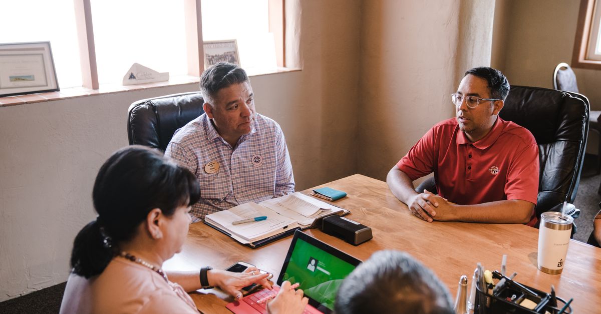 Colleagues discuss ideas in an office setting, emphasizing teamwork.