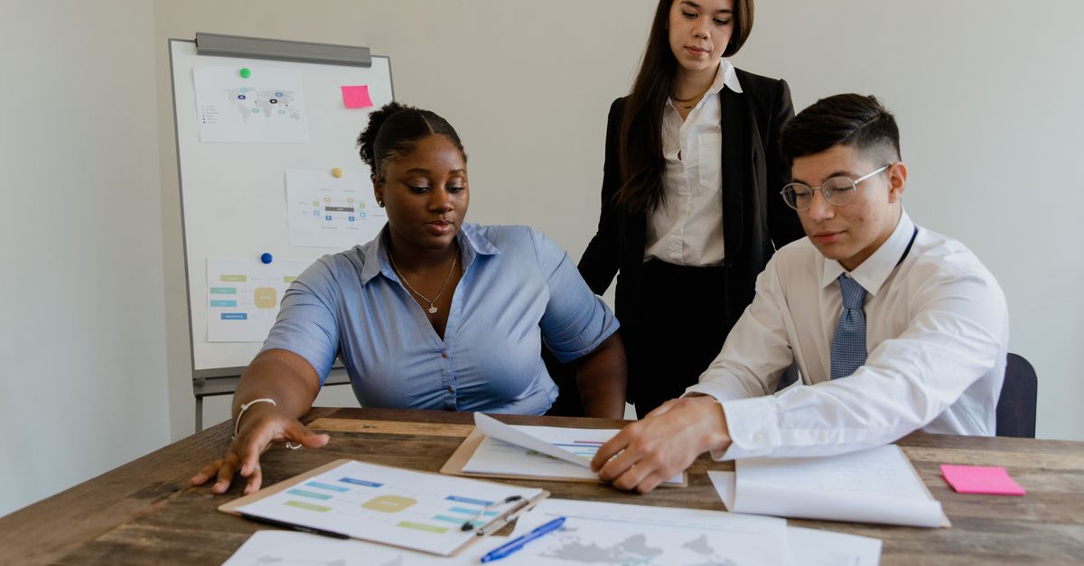 A diverse team discusses business strategies and processes in a modern office space.