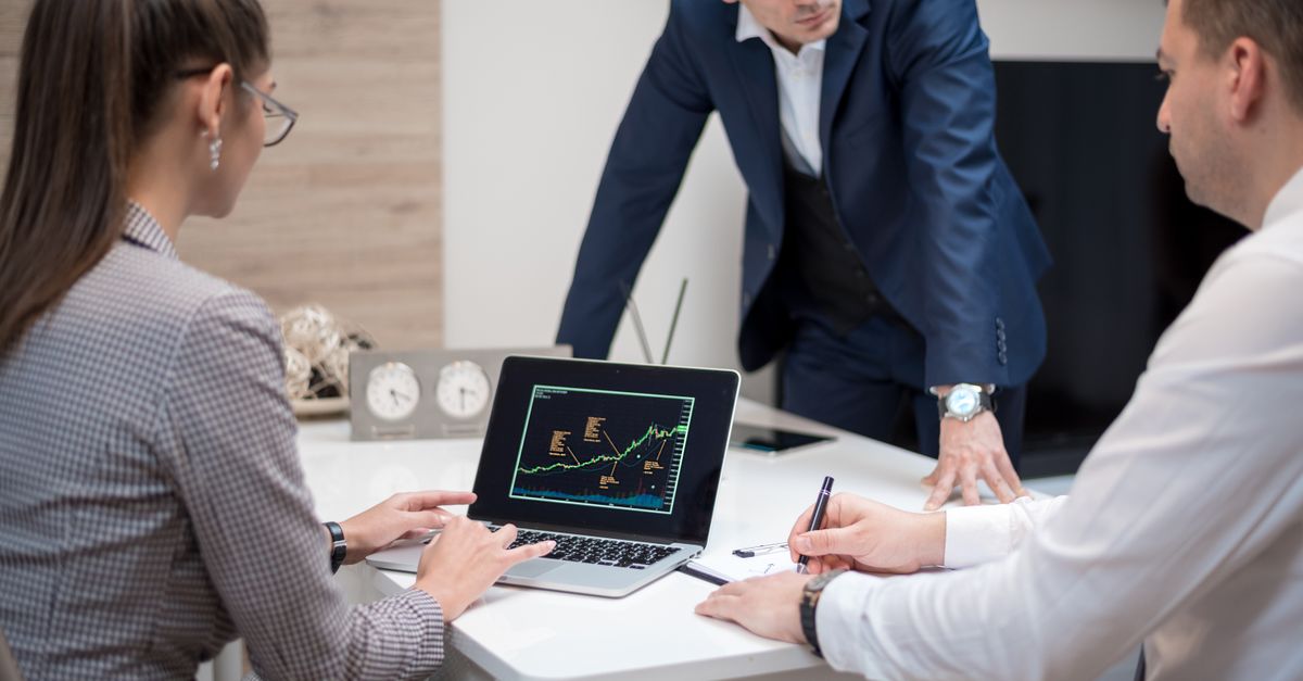Professional team analyzing stock market trends on a laptop during a meeting.