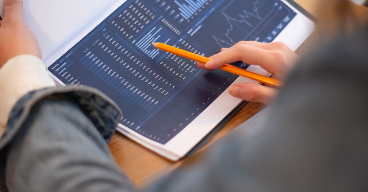 Focused image of hands analyzing business graphs and charts in a folder, highlighting data insights.