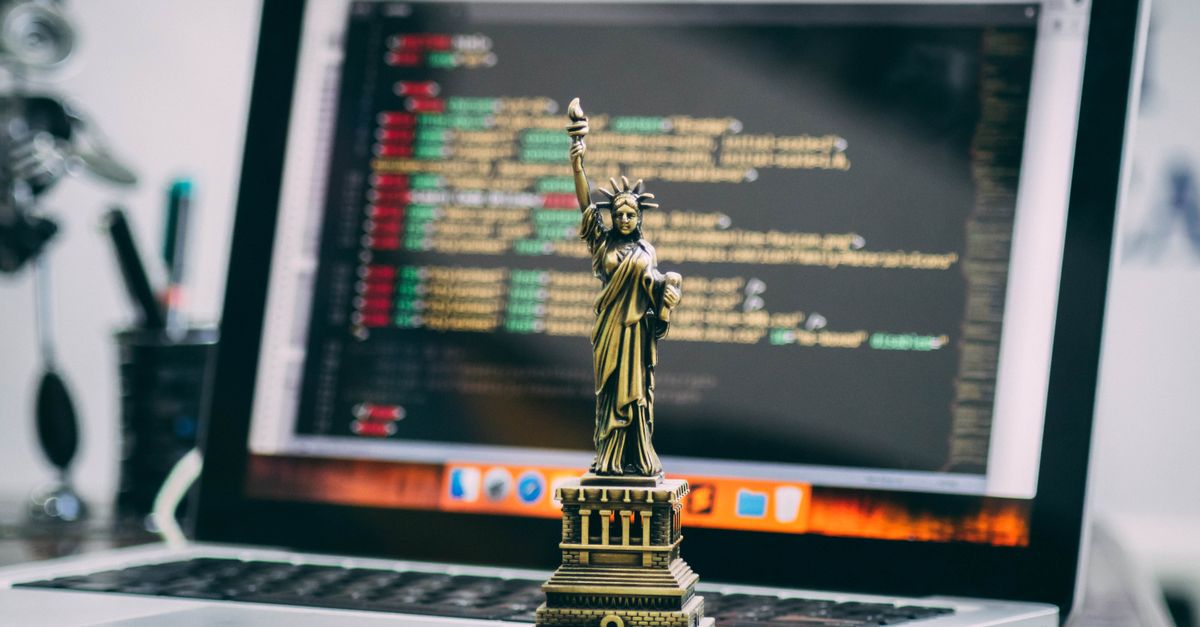 A miniature Statue of Liberty placed on a laptop displaying code, symbolizing freedom in technology.