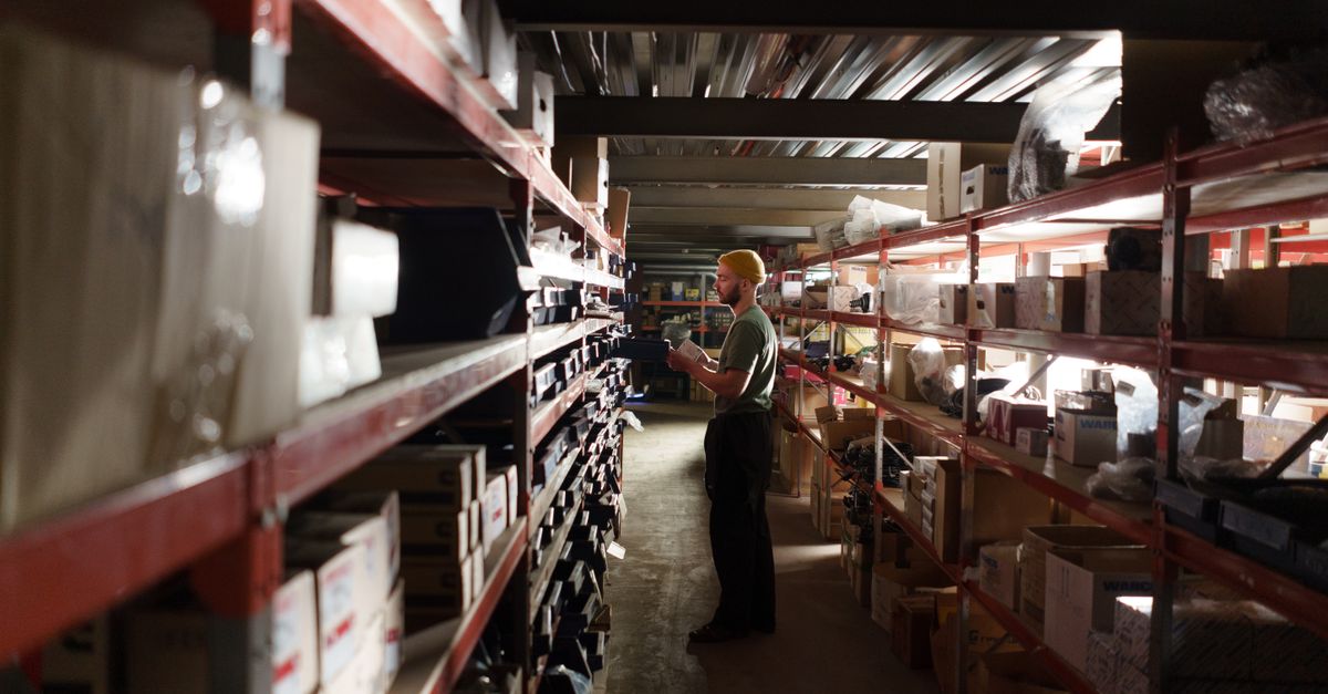 A warehouse worker sorting items on shelves in an organized storage space.