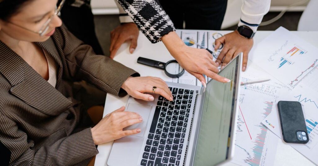 A group of colleagues working together on a laptop amidst documents. Collaborative teamwork in a modern office environment.