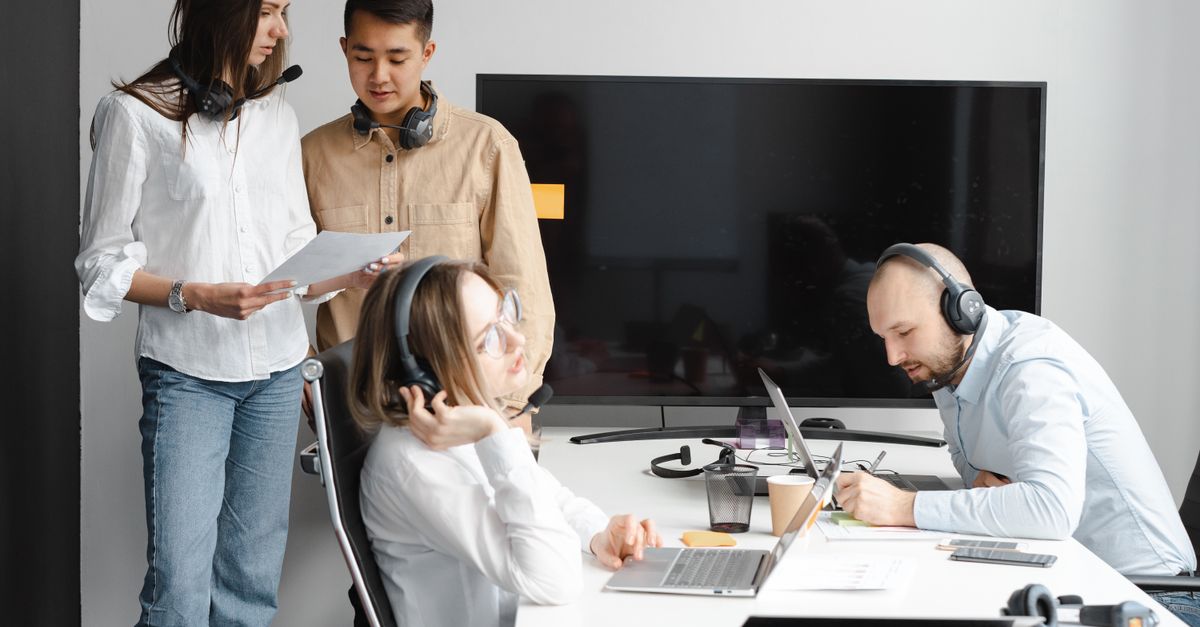 Diverse team of professionals collaborating in a modern office with tech gadgets and headsets.
