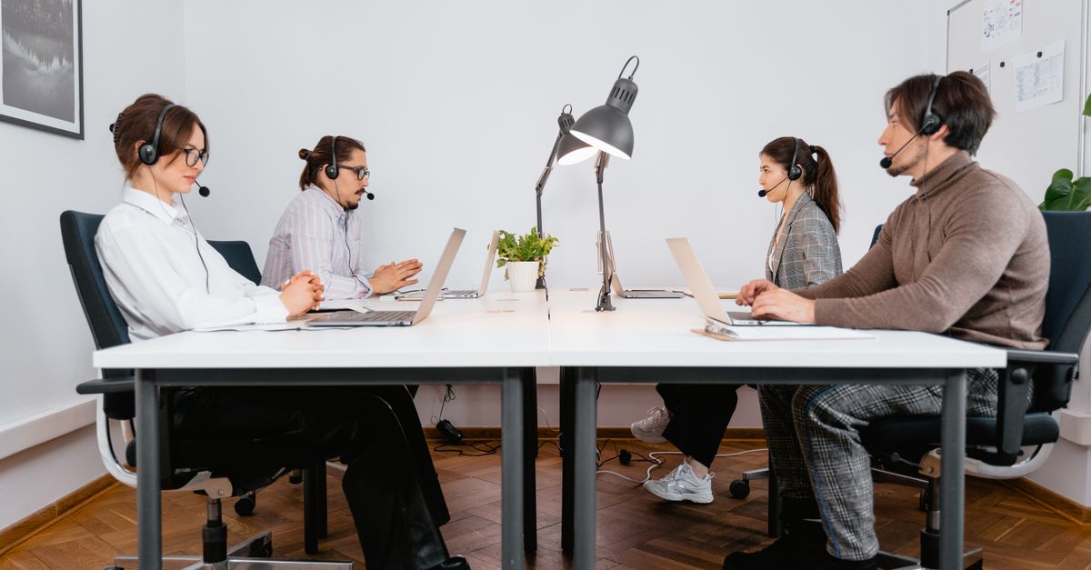 Call center team working with laptops and headsets in a modern office setting.