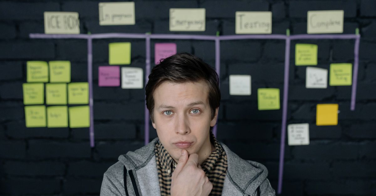 Pensive man in a startup workspace pondering tasks on a project board.