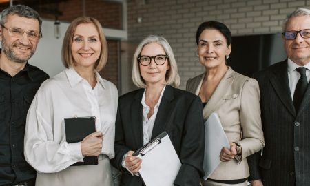 A diverse team of senior business professionals posing confidently indoors.
