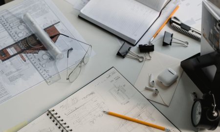 A busy architectural workspace featuring blueprints, sketches, and drafting tools.