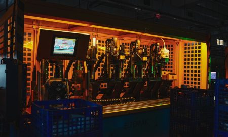 A complex piece of machinery in a dark industrial setting with vibrant lighting.