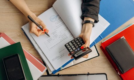 Accountant analyzing financial documents with a calculator on a desk, highlighting business tasks.