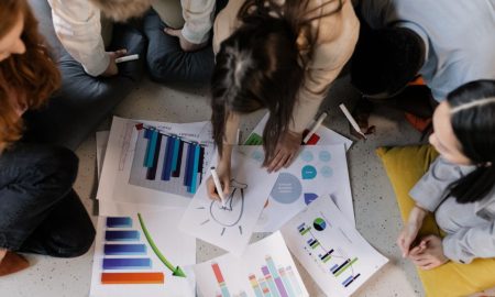 Overhead view of diverse team brainstorming on business strategy using charts and graphs.