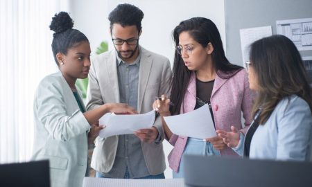 A diverse group of professionals engaged in a focused team meeting within an office environment.
