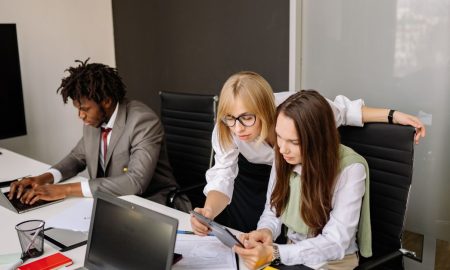Business team collaborating in a modern office setting with laptops and tablets.