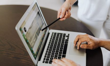 Two people collaborating on a project using a laptop, pointing and planning.