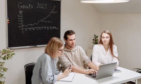 Coworkers collaborate in a modern office setting, planning and discussing 2021 goals.