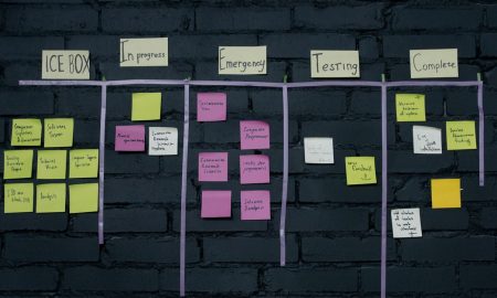 Top-down view of an office Kanban board with colorful sticky notes for task management and organization.