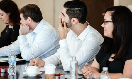 A diverse group of professionals engaged in a business meeting, collaborating and taking notes.