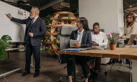 Business professionals engage in a team meeting with a whiteboard presentation in a modern office.