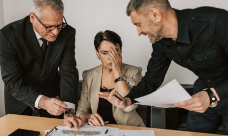 Business team in a tense meeting analyzing charts and reports at an office desk.