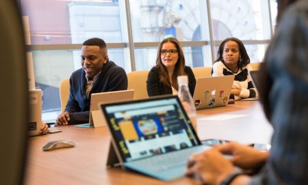 A diverse group of professionals working together on laptops in a modern office meeting room.