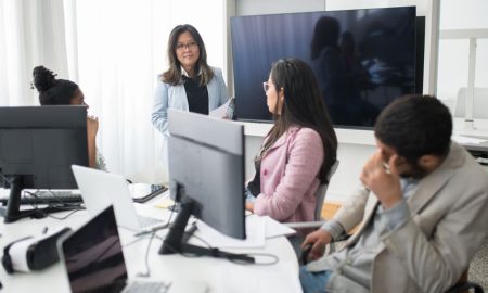 Professional team collaborating in a modern office environment with computers and screens.