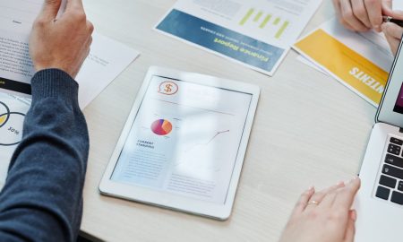 Top view of a business meeting table with digital devices and financial documents, showing collaboration.