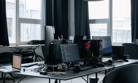 Contemporary workspace featuring computers, coding screens, and office essentials in a tech environment.