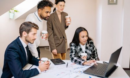 A diverse team collaborates in a modern office, using laptops and tablets for planning and brainstorming.