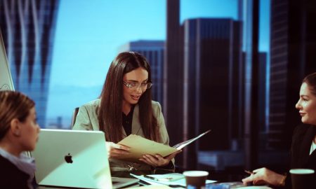 Three businesswomen engaged in a meeting at a Baghdad office with a city view.