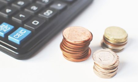 Close-up of stacked coins and a calculator symbolizing financial strategy and budgeting.